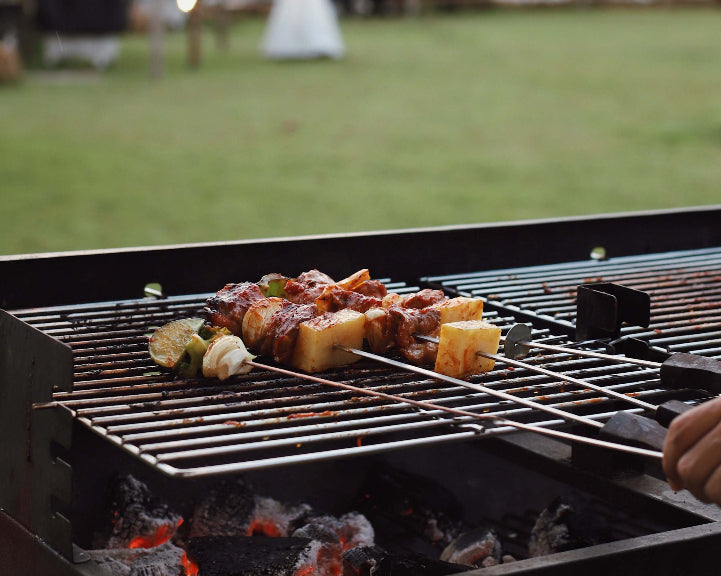 Closeup shot of a grill with skewers and vegetables.