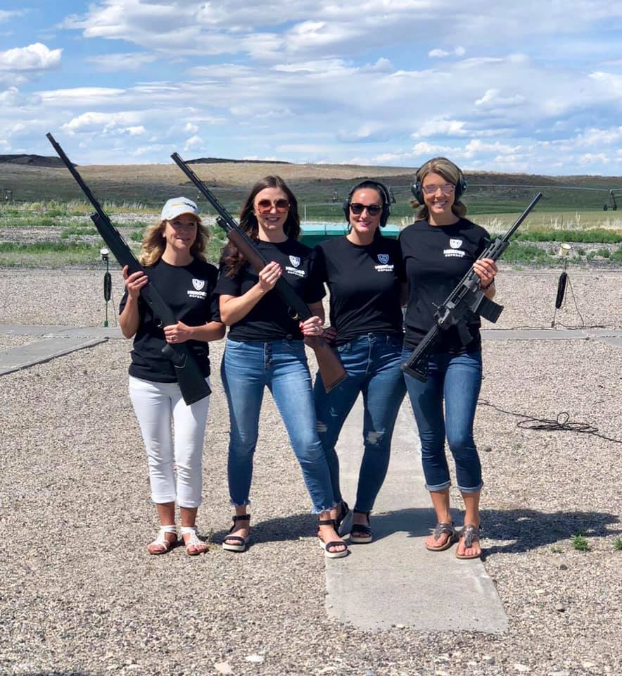 Four women holding rifles for a shooting range fundraiser for veterans, police.