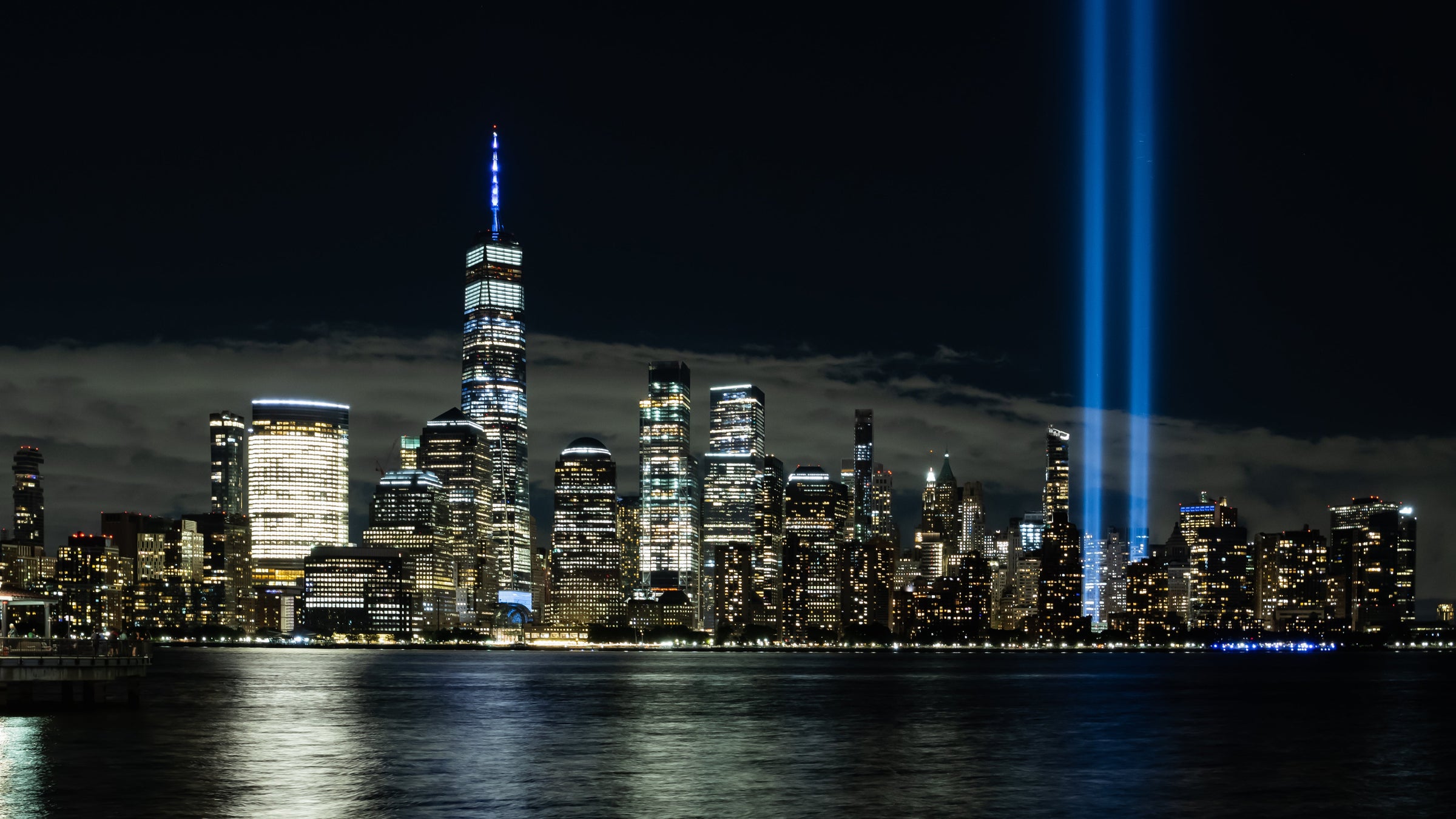 View from the bay of New York City, showcasing the blue lights that mark the 9/11 memorial.